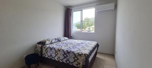 a small bedroom with a bed and a window at Apartamento próximo praia in Florianópolis