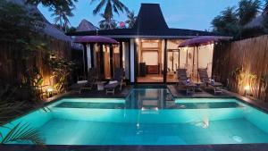 a swimming pool with chairs and a house at Meno Island Villas in Gili Meno