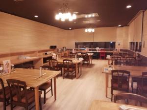 un restaurant vide avec des tables et des chaises en bois dans l'établissement Ryounkaku, à Kami-furano