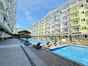 a hotel swimming pool with lounge chairs and a hotel at Ania Summer Rooms in Mactan