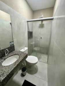 uma casa de banho com um WC e uma cabina de duche em vidro. em Morada do Lago em Palmas