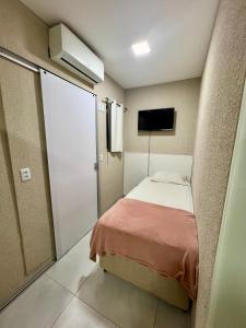 um pequeno quarto com uma cama e uma televisão em Morada do Lago em Palmas