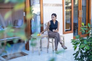 a woman sitting in a chair next to a table at Sanata Yoga Guesthouse in Canggu