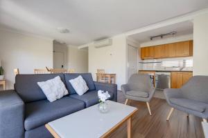 a living room with a blue couch and two chairs at 2X1 Comfy Apartment in Perth CBD in Perth