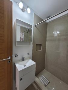 La salle de bains est pourvue d'un lavabo blanc et d'une douche. dans l'établissement Gente del Sur - Marinas Towers, à Ushuaia