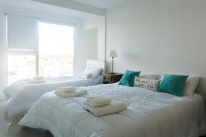 Habitación blanca con 2 camas y toallas. en Gente del Sur - Marinas Towers en Ushuaia