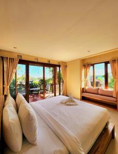 um quarto com uma grande cama branca e janelas grandes em BUDA AMITABA em Ubud