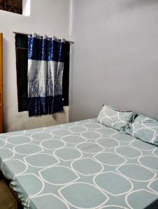 Schlafzimmer mit einem Bett mit blauer und weißer Bettwäsche und einem Fenster in der Unterkunft Tandon Lodge in Varanasi