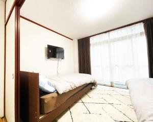 a bedroom with two beds and a large window at Feliz Kumamoto in Kumamoto