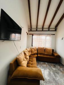 a living room with a couch and a flat screen tv at Hostal El Palacio Del Descanso in Villa de Leyva