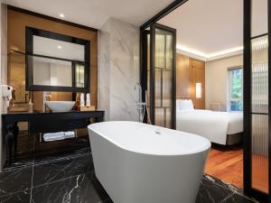 a bathroom with a tub and a sink and a bed at Minerva Premium Hotel in Hanoi