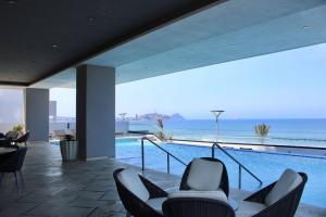 a house with a swimming pool and chairs and the ocean at Altomare hermoso depa con vista al mar in Mazatlán