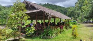a group of people standing under a hut at Tiu Batu Homestay in Bangsal
