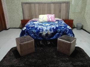1 dormitorio con 1 cama con 2 taburetes al lado en La Perla Cuencana Hostal, en Cuenca
