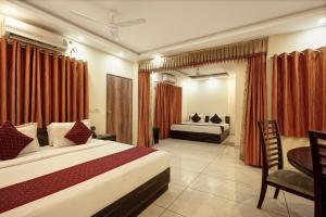a bedroom with two beds and a table and a desk at Hotel New City Lite in New Delhi