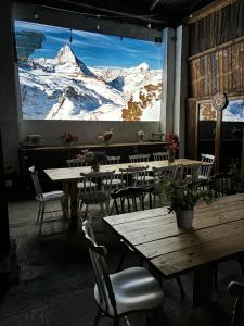 ein Restaurant mit Tischen und Stühlen und ein großes Fenster mit schneebedeckten Bergen in der Unterkunft Ranczo Łubowice - wynajmij sobie spokój in Łubowice