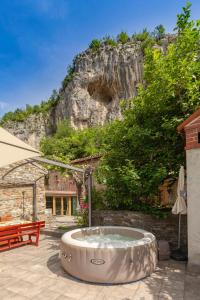 UNDER THE ROCK Osp في Osp: حوض استحمام ساخن في فناء مع جبل