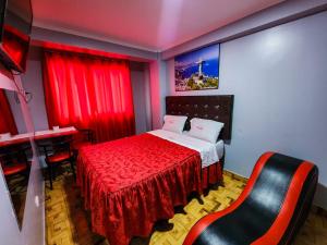um quarto com uma cama com cortinas vermelhas e uma cadeira em hostal paris em Lima