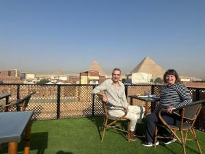 un uomo e una donna seduti su un balcone con piramidi di Nefertari Pyramids View Inn a Il Cairo