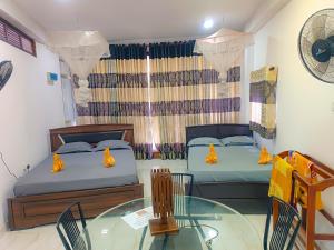two beds in a room with a glass table and chairs at SECRET MIRAGE Ella in Ella