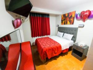 um quarto com uma cama com uma colcha vermelha em hostal paris em Lima