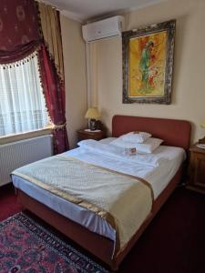 a bedroom with a large bed with a picture on the wall at Hotel Grande in Celje
