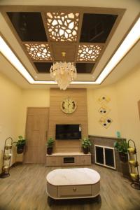 a living room with a tv and a chandelier at CATALEYA Home Stay in Kotagiri +10 photos
