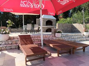 two benches sitting under a red umbrella on a patio at Villa Katarina in Tivat