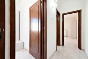 a hallway with a wooden door and a mirror at LuEDa House - Trasfertisti e Turisti in Surbo +29 photos