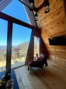 a child sitting in a chair in a room with a large window at Wayside Cottage in Batumi