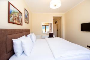 a bedroom with a white bed and a flat screen tv at Hotel Opera Jaz in Budva
