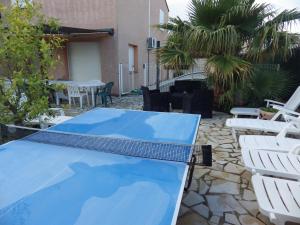 een tafeltennistafel en stoelen op een patio bij villa climatisée avec grande piscine in Saint-Laurent-de-la-Salanque