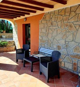 a patio with chairs and a stone wall at Gelsi Holiday Home La Maddalena in La Maddalena
