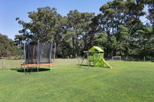 two playground equipment in a field with trees at Black Swan Retreat in Metung