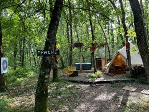 a tent in the woods with a sign that reads aragog at APACHE in Loubès-Bernac