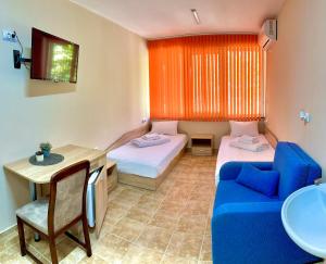 a room with two beds and a blue couch at Комплекс Лабиринт in Sliven