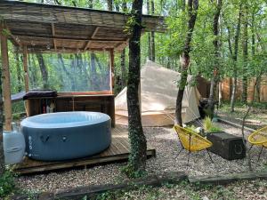 a hot tub and a tent in the woods at APACHE in Loubès-Bernac