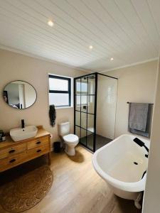 a bathroom with a tub and a sink and a toilet at The Old Oke Riverhouse in Malgas