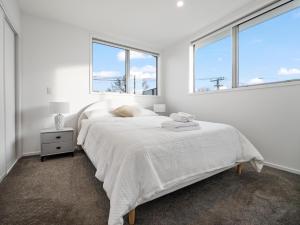 1 dormitorio blanco con 2 camas y 2 ventanas en Central City Heaven Spa, en Christchurch