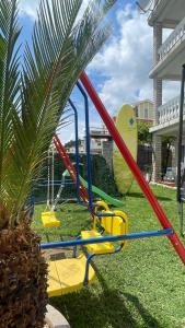 un parque infantil en un patio con un columpio en Family House with pool & sea view, en Bijela