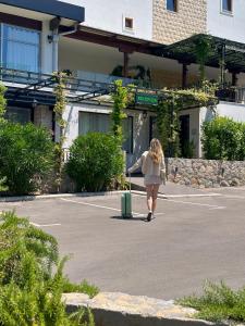een vrouw die op een parkeerplaats loopt met een koffer bij Hotel Opera Jaz in Budva
