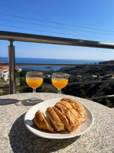 a plate of bread and two glasses of orange juice at Myrtoan Sea View Apartment in Velanídhia +24 photos