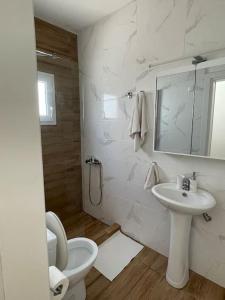 a white bathroom with a toilet and a sink at Myrtoan Sea View Apartment in Velanídhia
