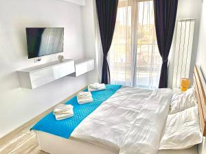 Schlafzimmer mit einem weißen Bett und einem TV in der Unterkunft Mamaia-Nord Boutique Apartments in Mamaia Nord – Năvodari