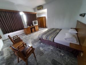 a bedroom with a bed and a desk and two chairs at Hotel kumala samudra in Tjikakaka
