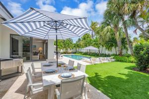 a dining table with an umbrella in a backyard at Coastal Style Haven Beach Proximity Heated Pool Tranquility Manatee Ranch Key RESlDENCES in Fort Lauderdale