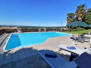 a swimming pool with a table and chairs and an umbrella at La Bella Vite in Moncalvo