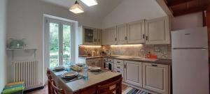 a kitchen with white cabinets and a table and a refrigerator at La Mansarda sul Golfo in Portovenere