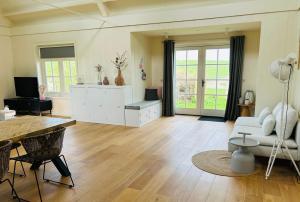 uma sala de estar com um sofá branco e uma mesa em Villa Nieuwland B&B em Den Oever