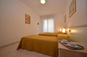 a hotel room with two beds and a table with cups at Residenza Le Acacie in Bibione